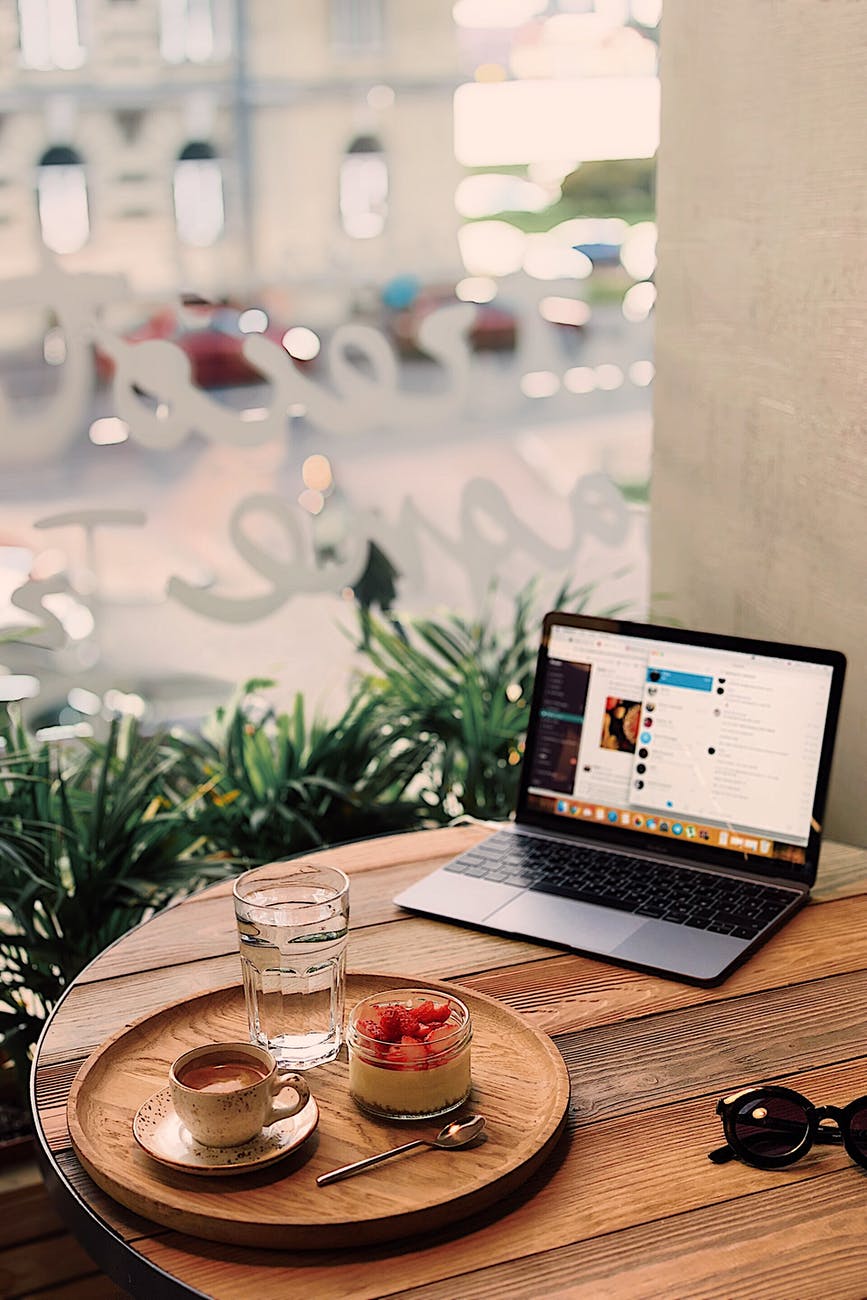 tray of fruits and coffee near powered on laptop on brown table