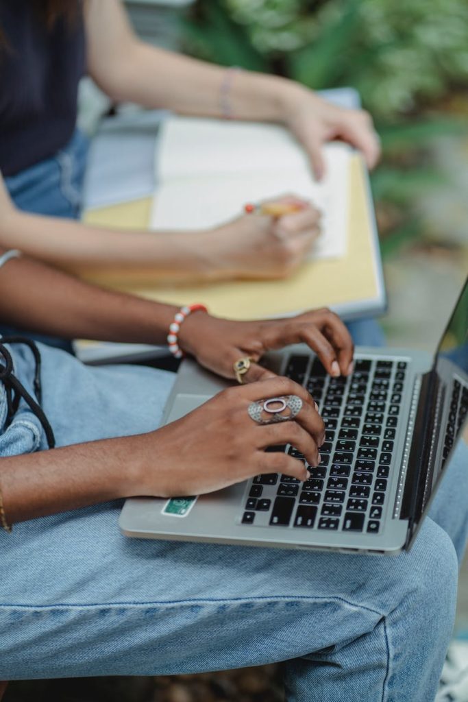 female friends using computer writing notes in notebook